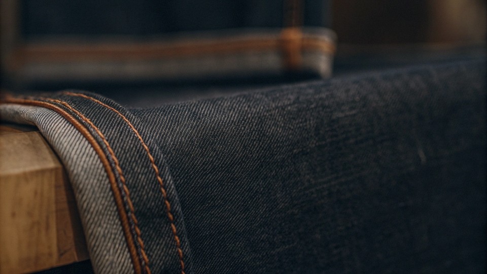 Selvedge denim is a tightly woven fabric made on traditional shuttle looms, producing a clean, self-finished edge that prevents unraveling and enhances durability.
