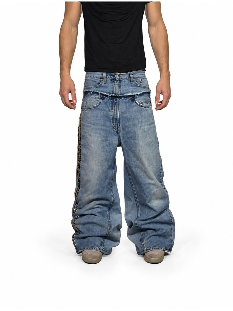 Model wearing light blue double-waist baggy jeans with patterned side trim and stacked full-length hems.