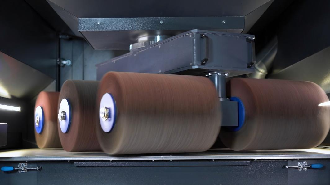 Abrasive brush descaling a metal plate, showing the contrast between the scaled and cleaned surfaces