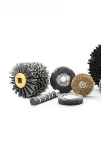An assortment of different abrasive brush shapes, including wheel, cup, end, and cylindrical brushes laid out on a workshop bench.