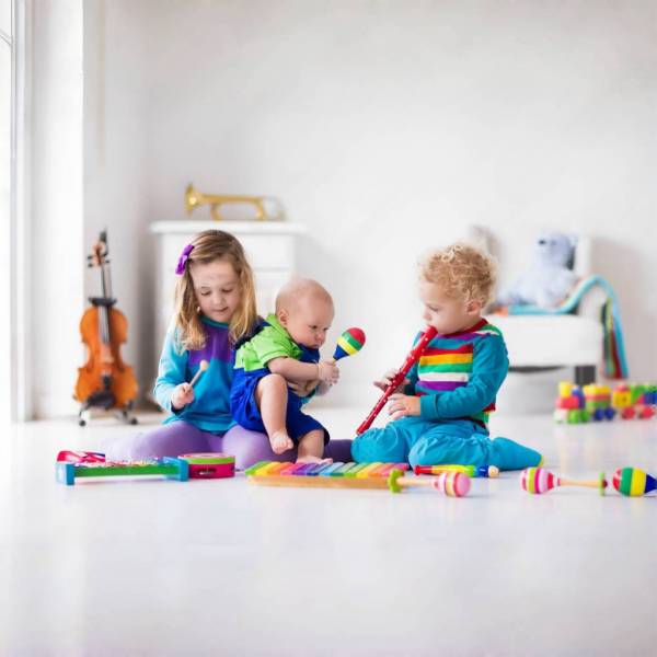 Children playing together with wooden maracas and xylophones