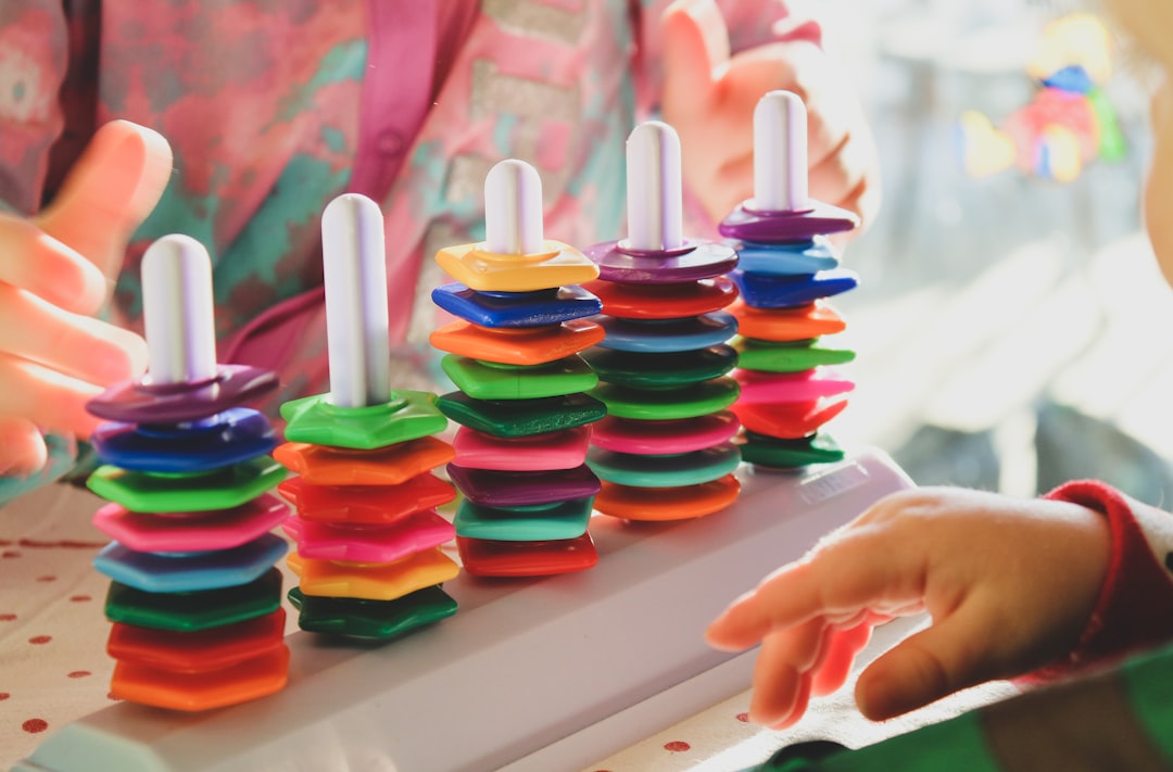 A child intently focused on stacking a colorful wooden rainbow toy.