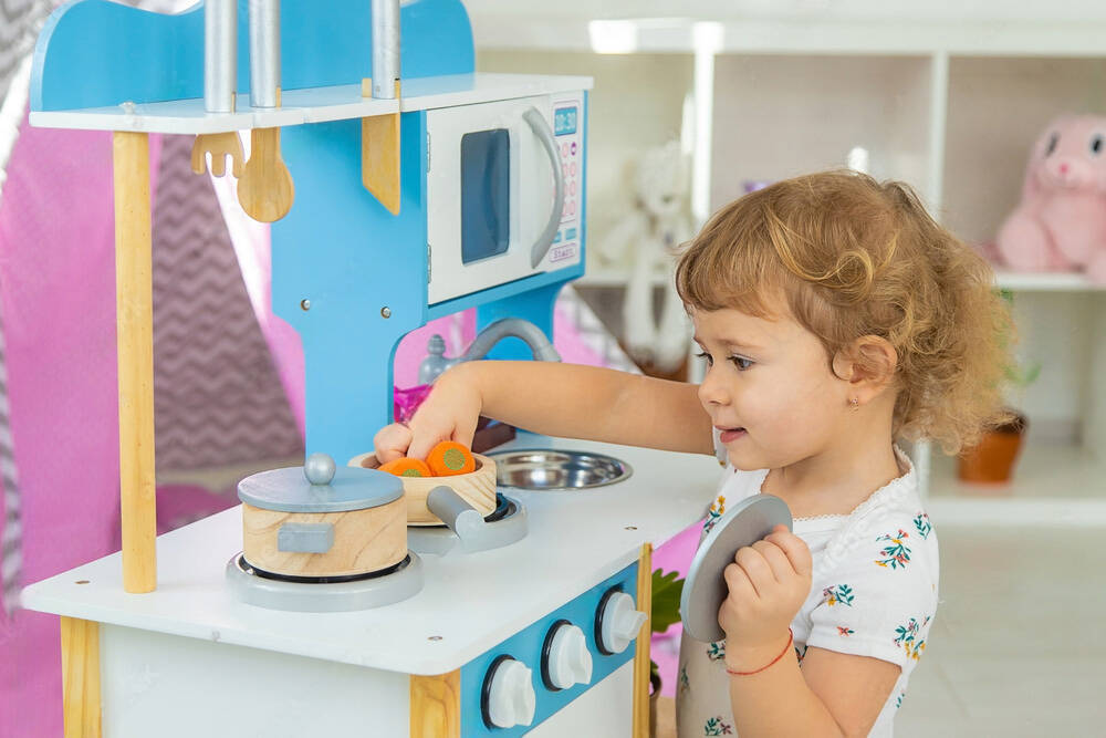 Toddler enjoying a wooden play kitchen