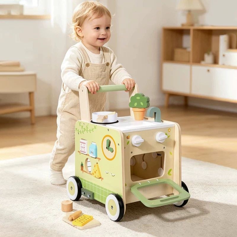 Toddler pushing the wooden activity walker kitchen trolley across a playroom