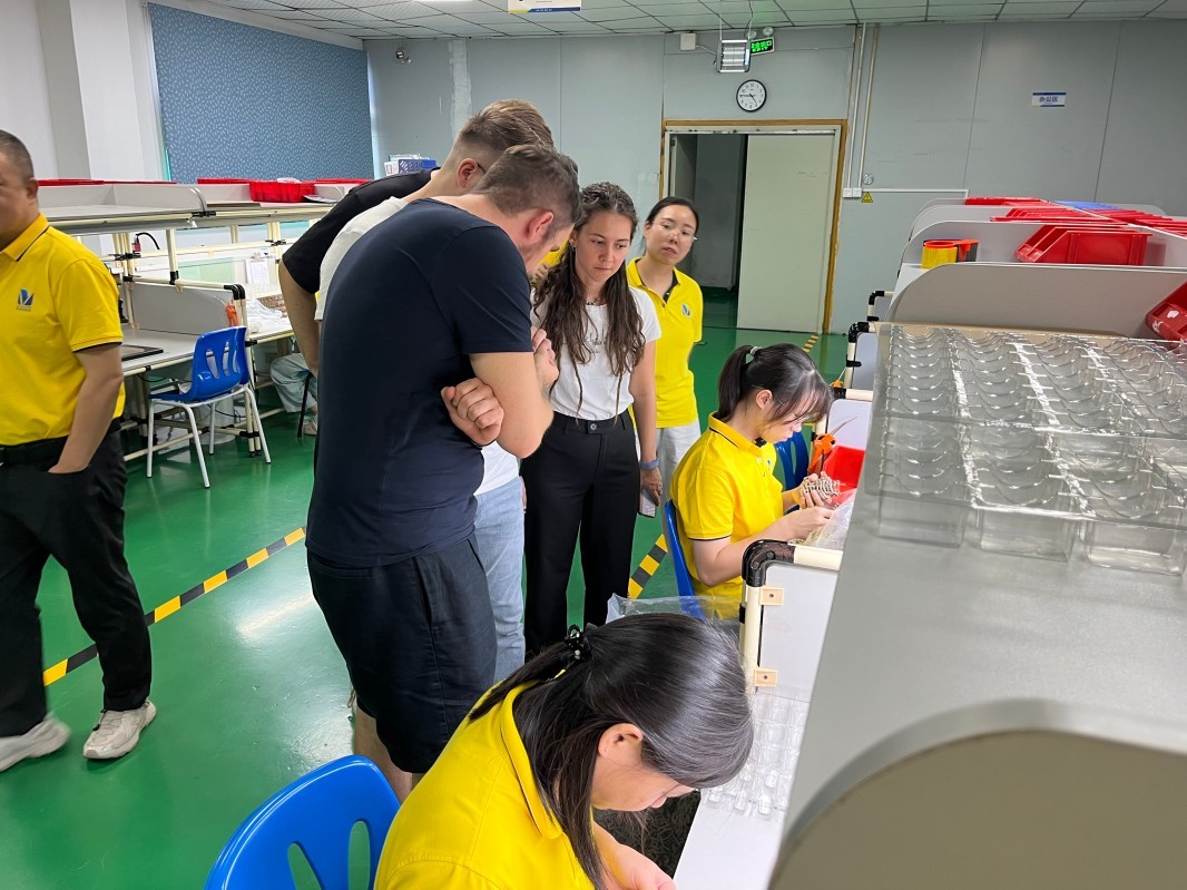 International visitors examine manufactured components at a SiliconePlus factory workstation