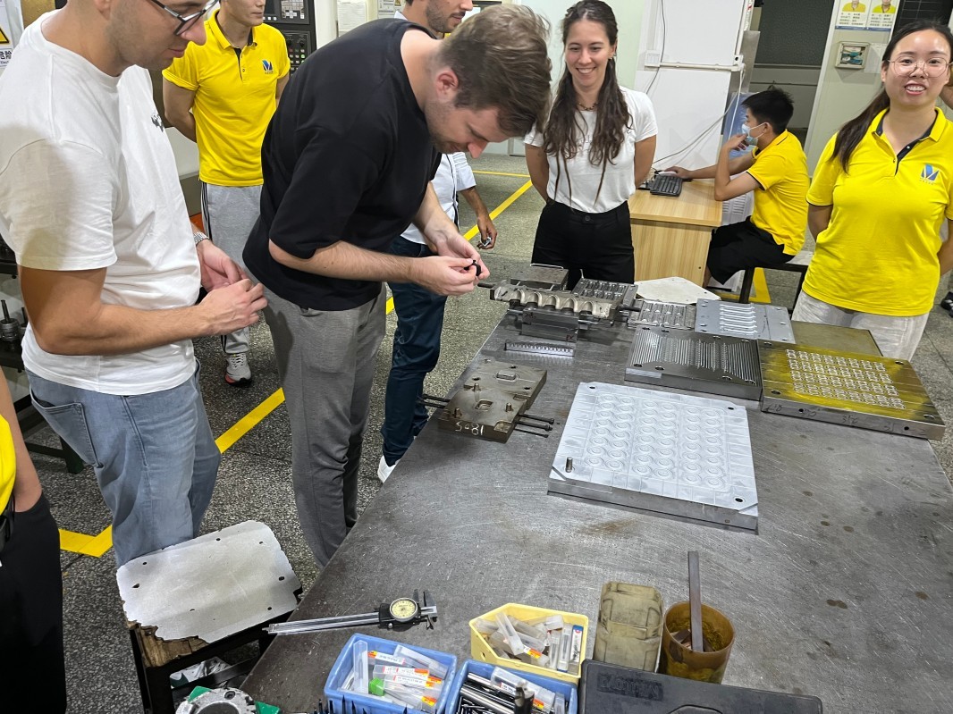 International customers review manufactured parts at a production workstation