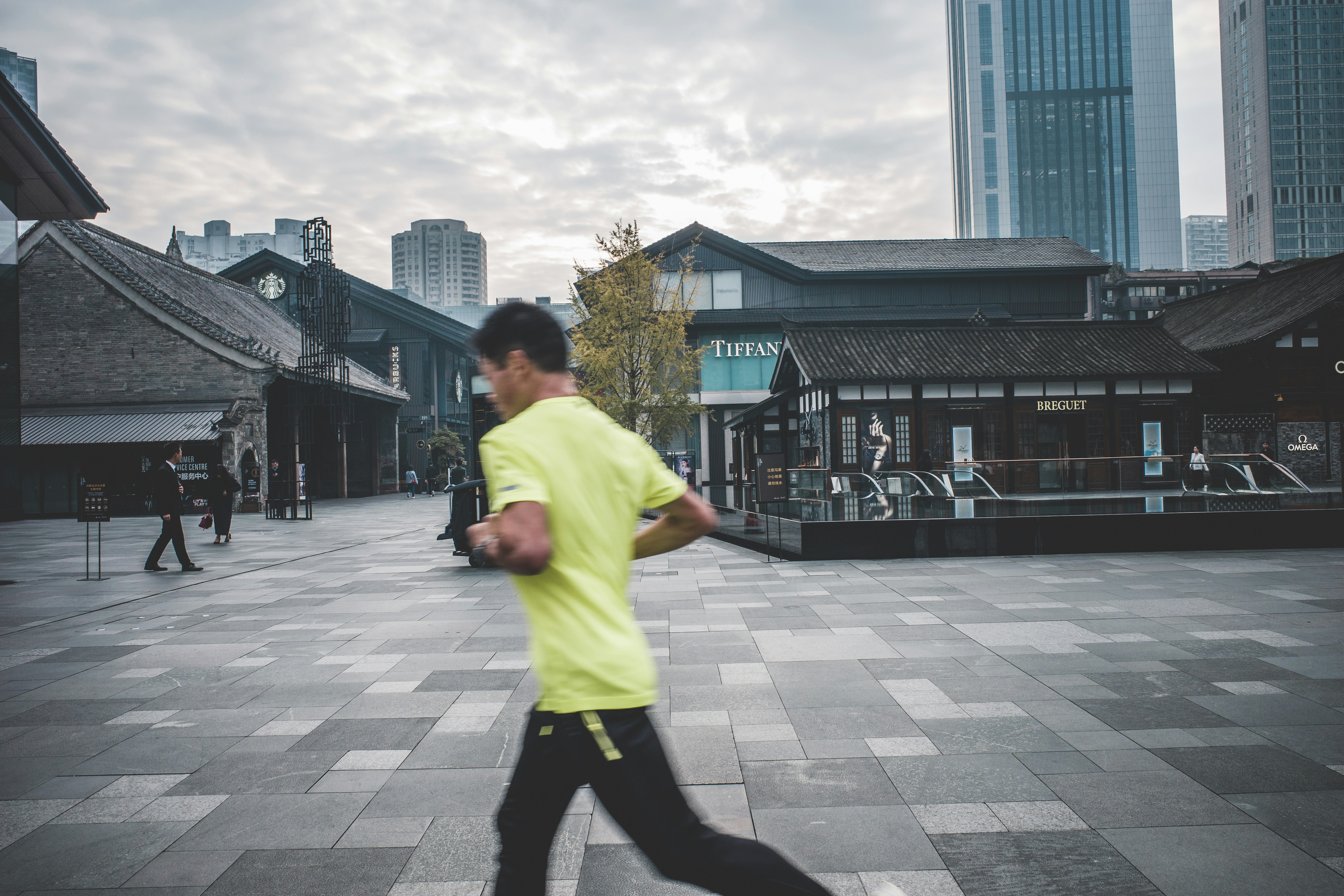 A man wearing stylish tapered joggers and a performance t-shirt walking in a city environment, transitioning from gym to street style