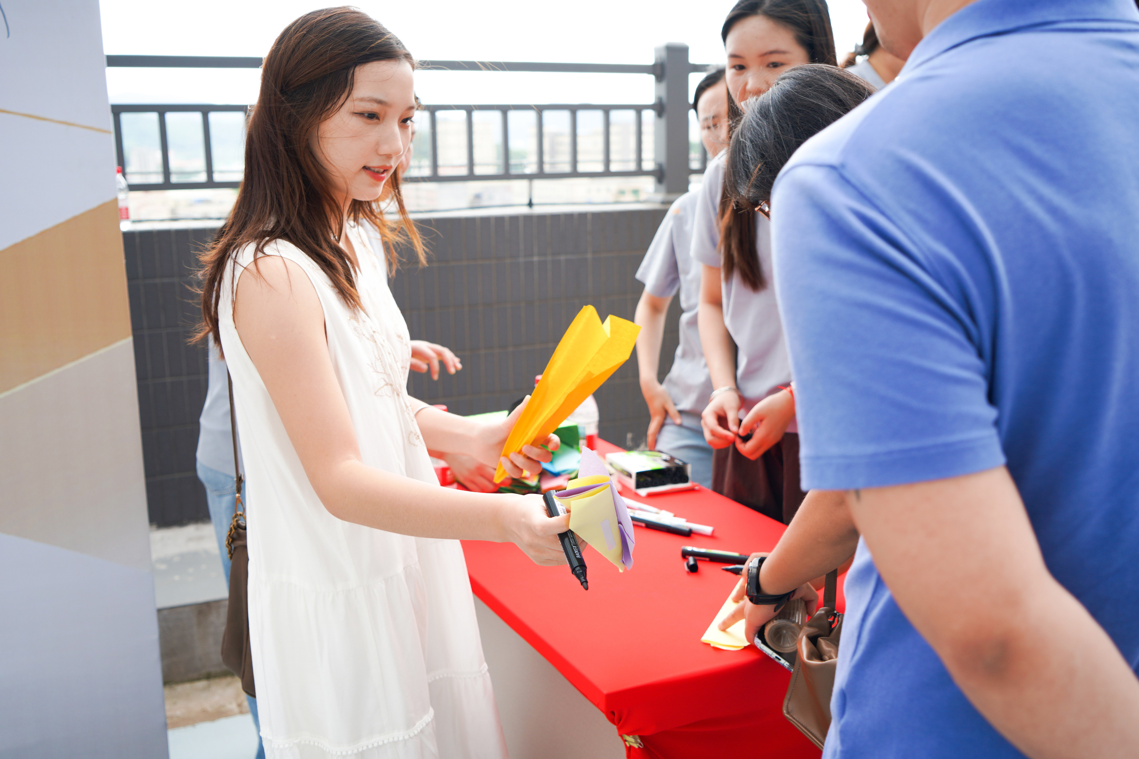 Guests writing wishes on paper planes at Jdttex Faybric relocation signature booth
