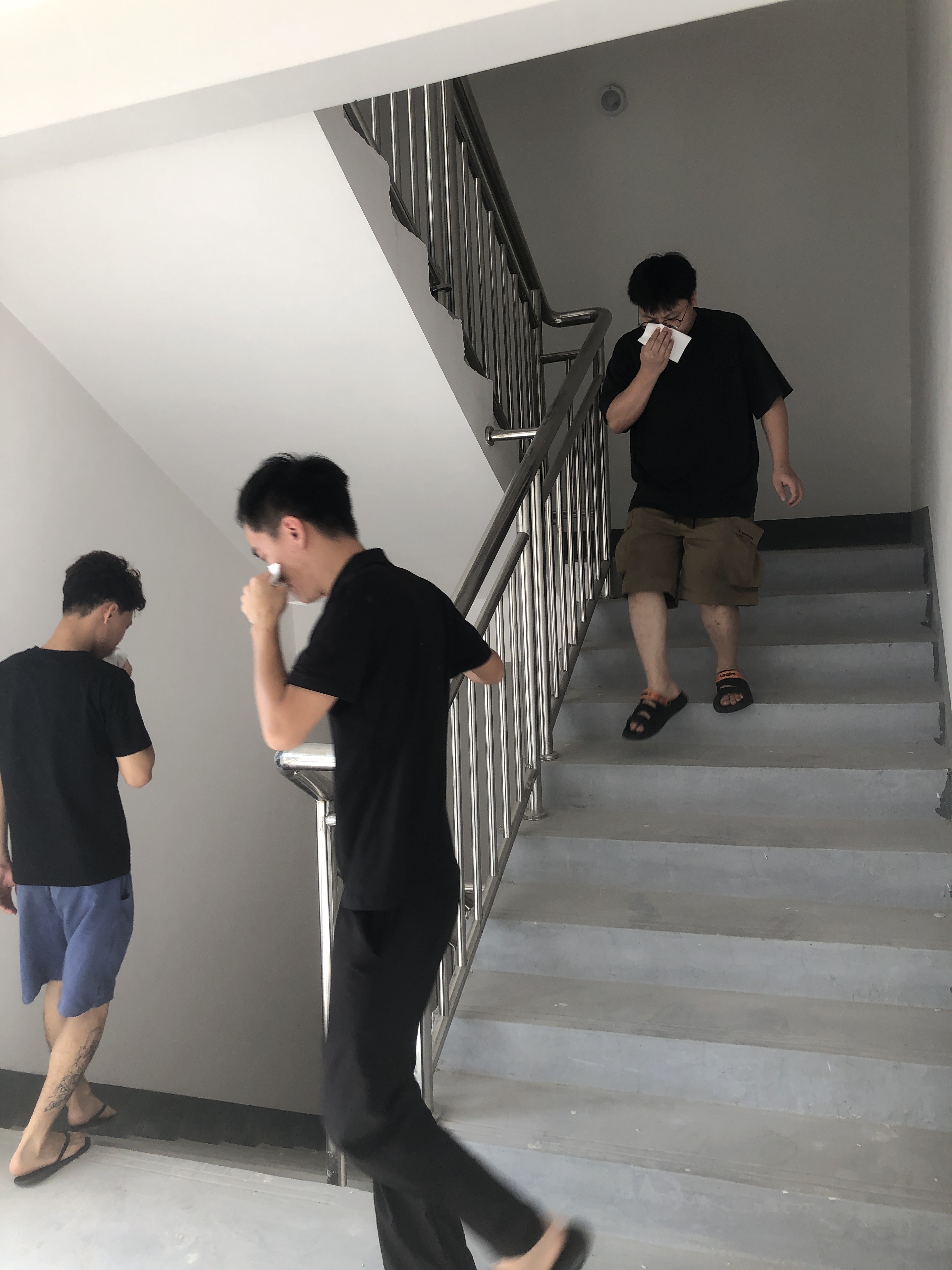 Employees evacuate stairwell with tissue covering nose during smoke escape simulation