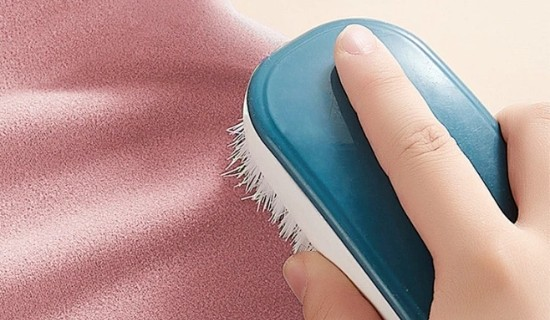 ALT: Uso de un cepillo de limpieza para eliminar las bolitas en la tela elástica de nailon, elastano y poliamida, cuidado diario de la tela para ropa deportiva de yoga.