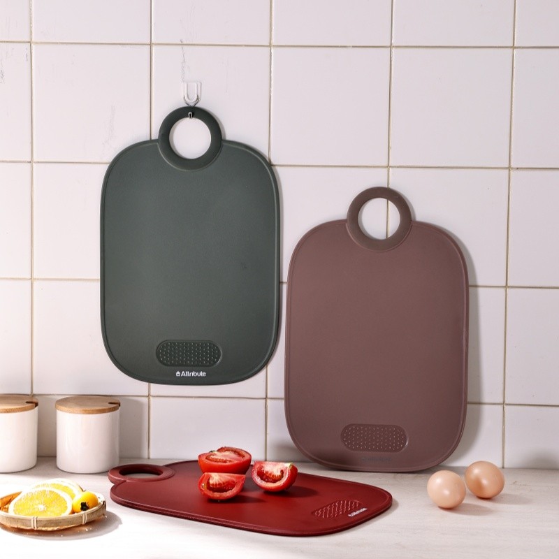A collection of safe, non-toxic kitchenware including a wooden cutting board, stainless steel pans, and glass containers.