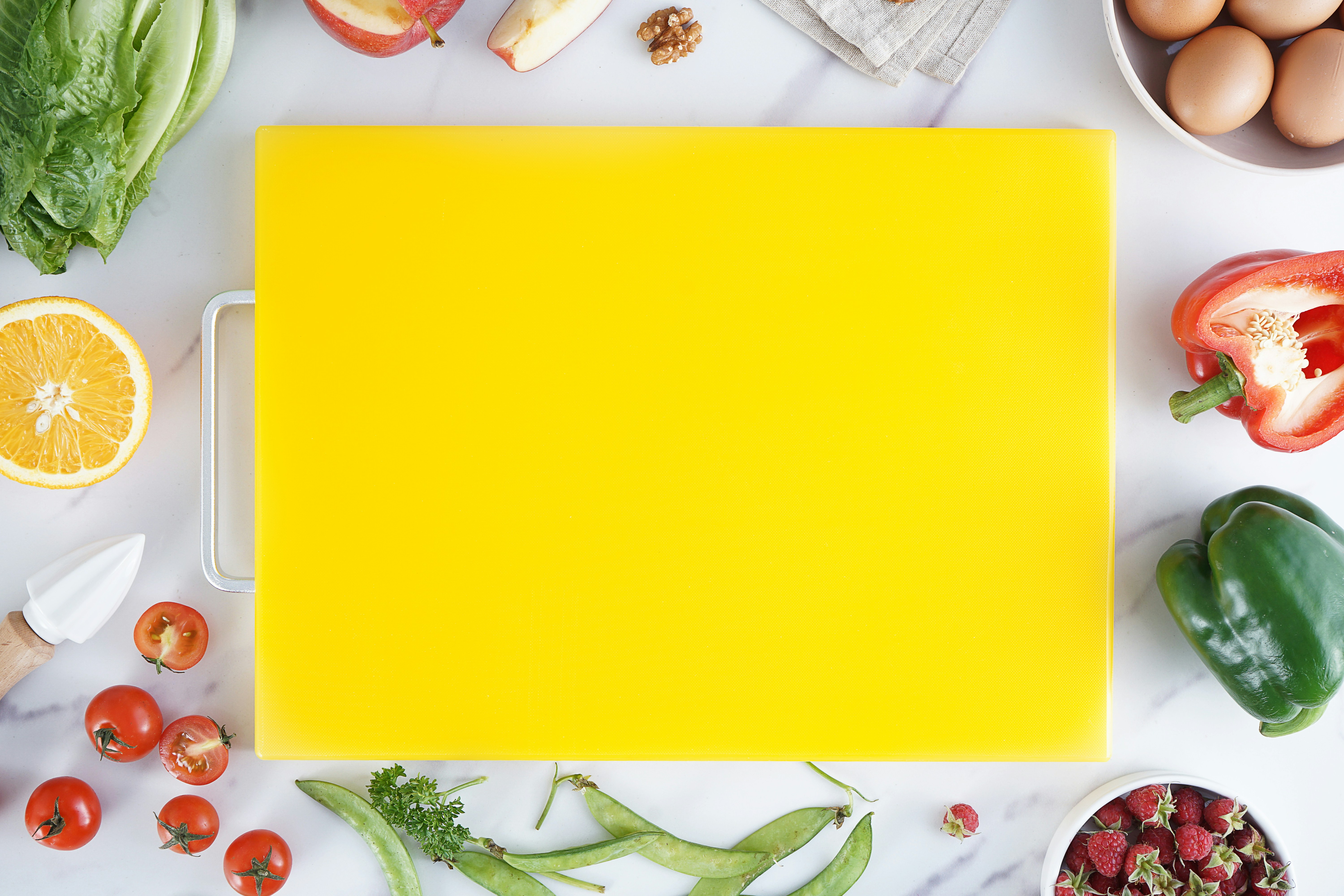 A double-sided plastic cutting board showing one side for meat and one for vegetables.