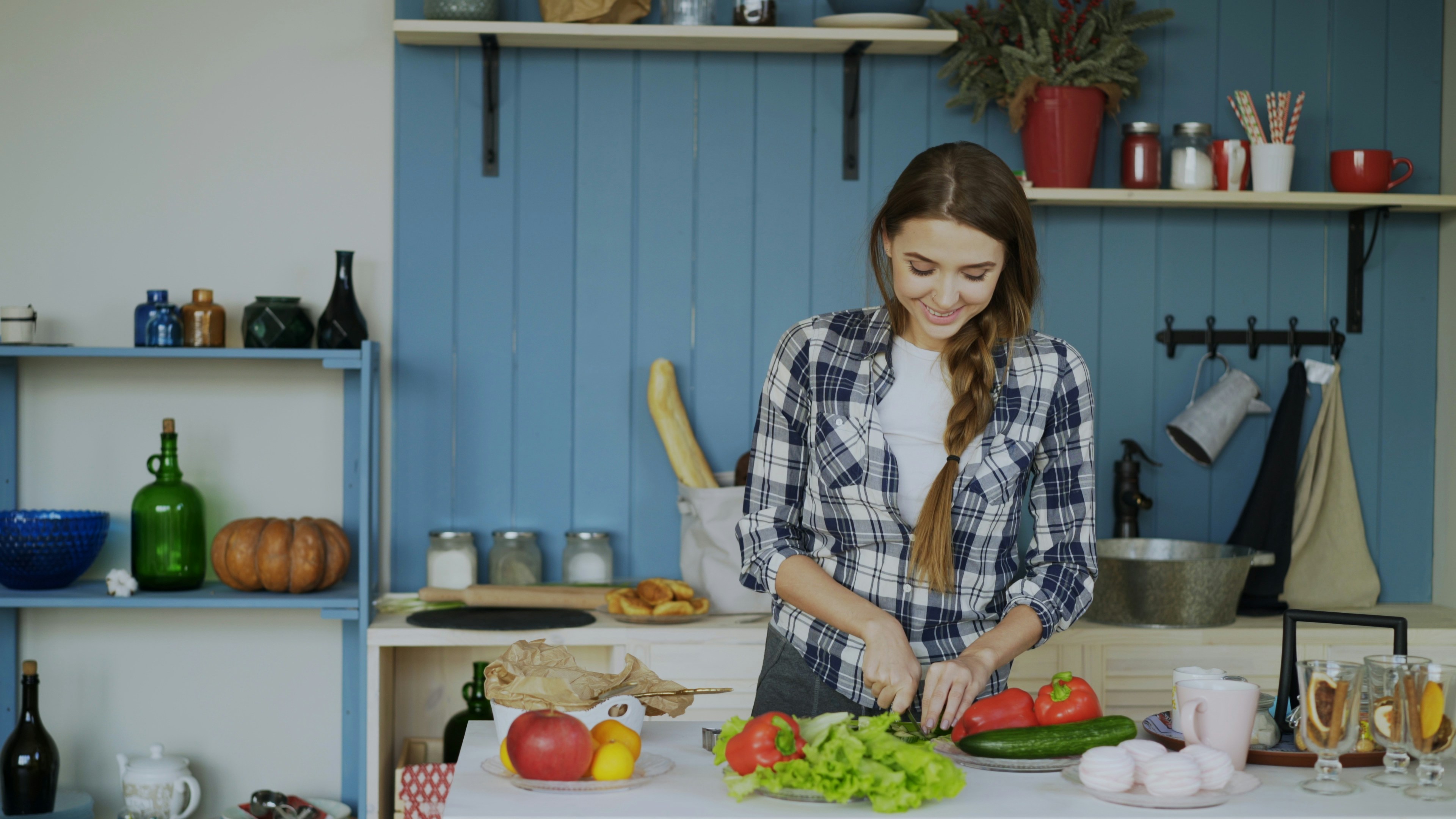 A person looking frustrated while trying to slice a tomato with a dull knife on a kitchen counter.