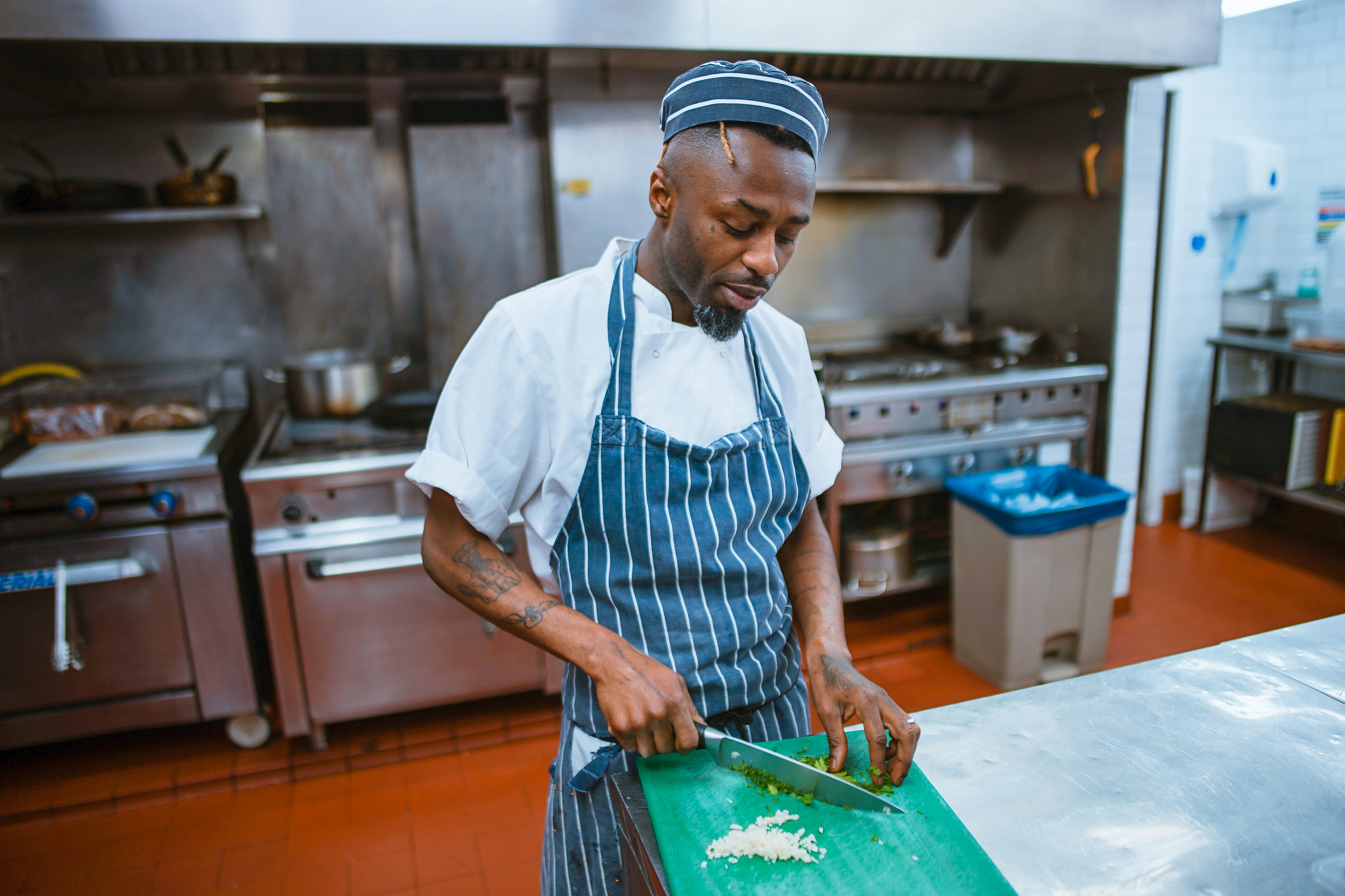 A chef preparing raw chicken on a stainless steel cutting board in a clean kitchen