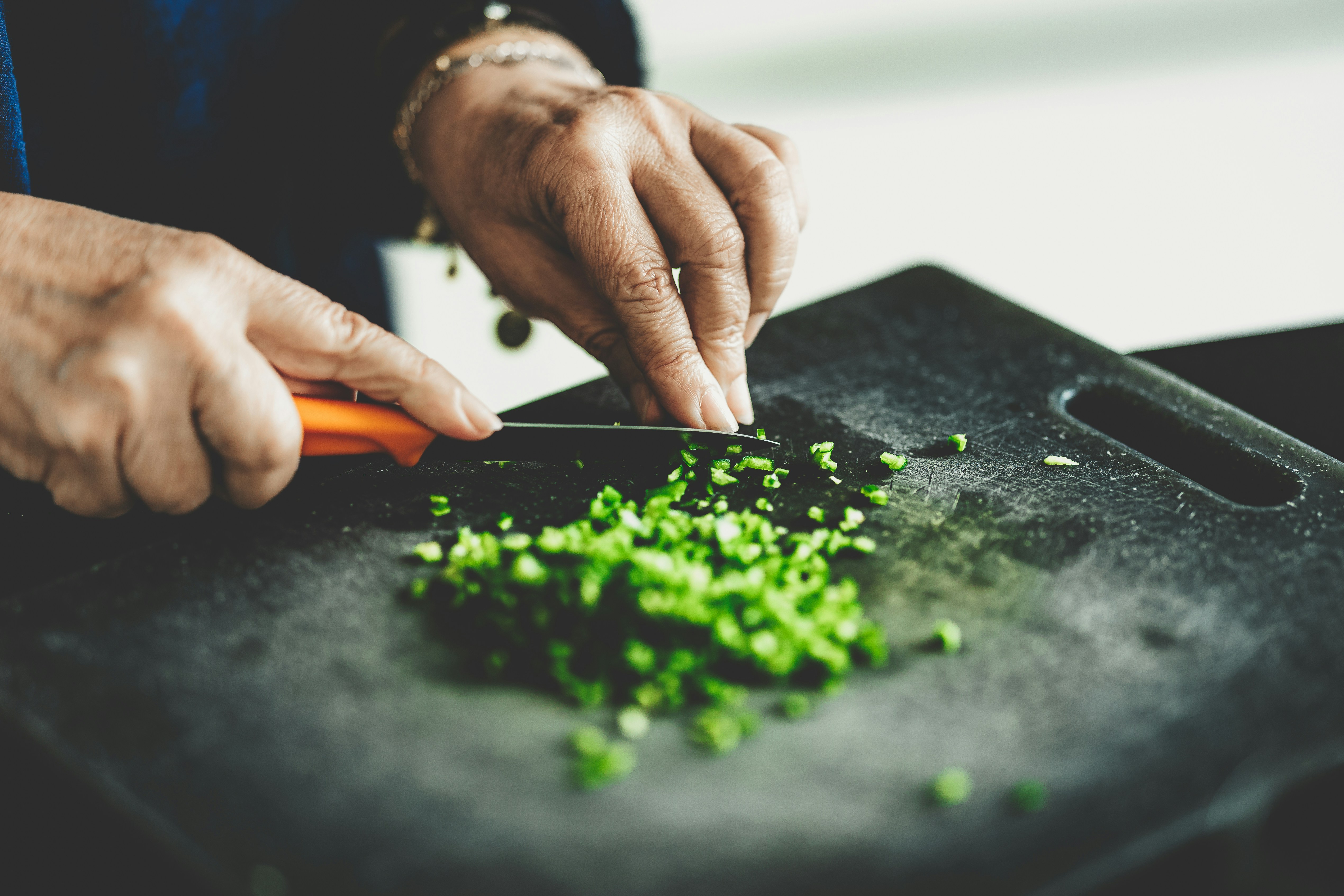 Professional rubber cutting board in use A professional chef using a large, black rubber cutting board to finely chop herbs, showcasing its stability.