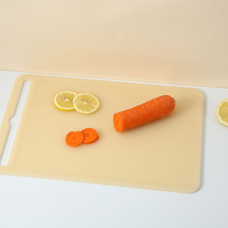 A person chopping vegetables on a bamboo board next to a clean HDPE board.