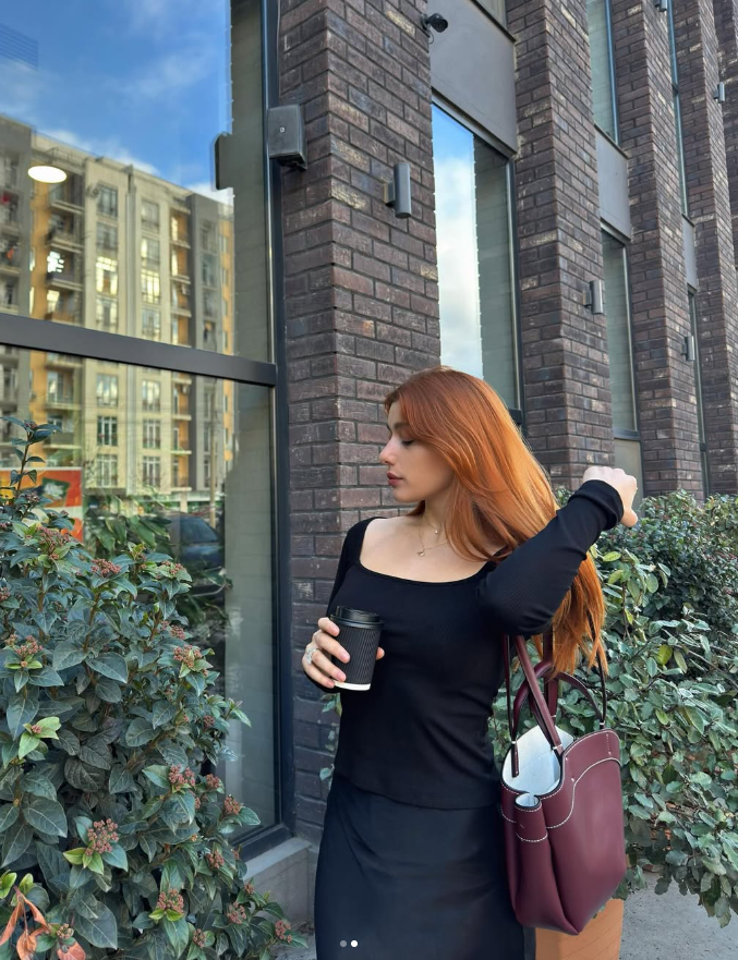 Woman in black top and skirt with coffee on city street