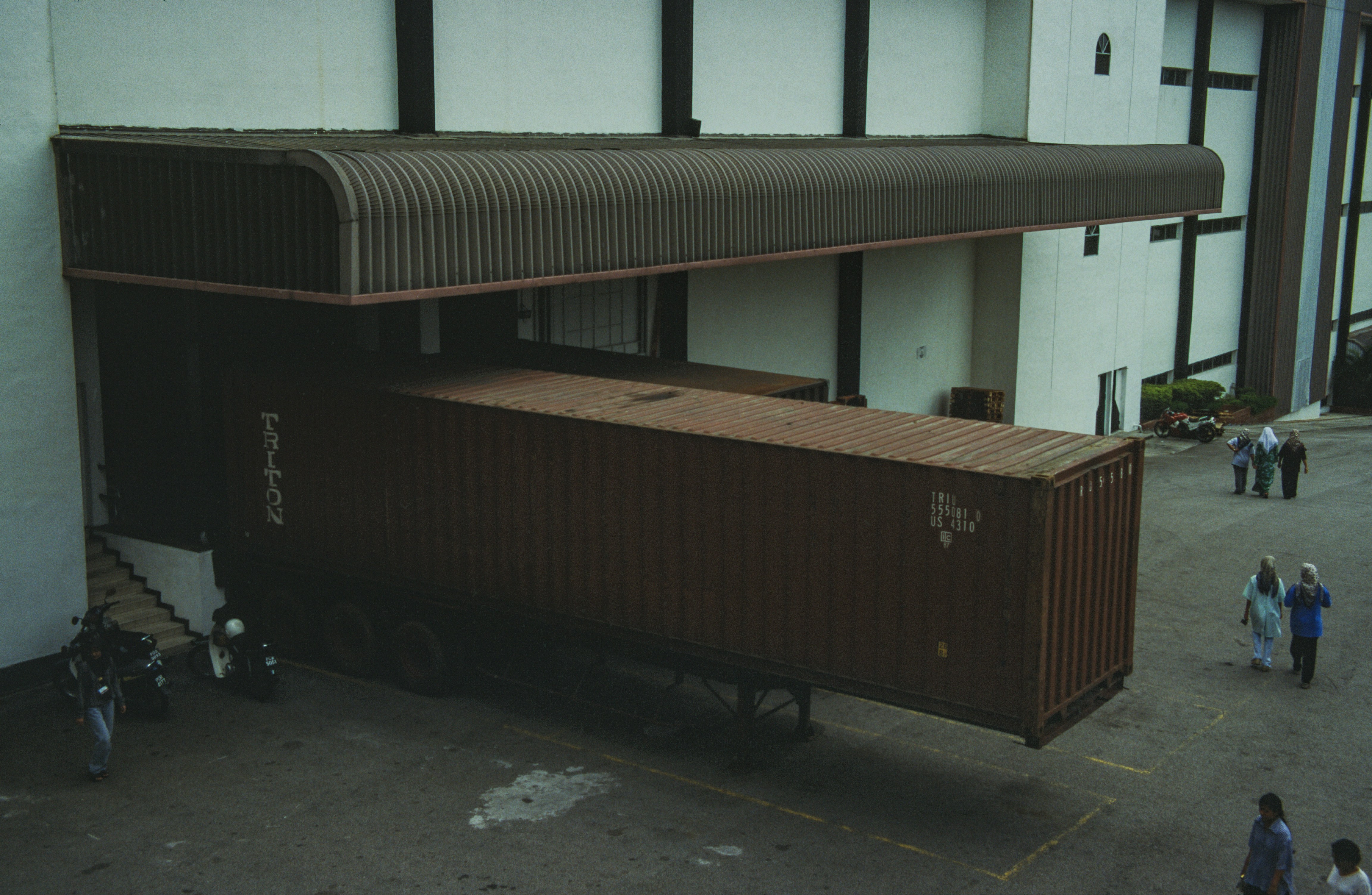 A warehouse manager with a tablet, assessing the layout of a loading dock area where a flexible conveyor will be used.
