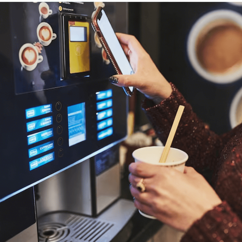Bamboo coffee stirrer in a paper cup at an automated vending station