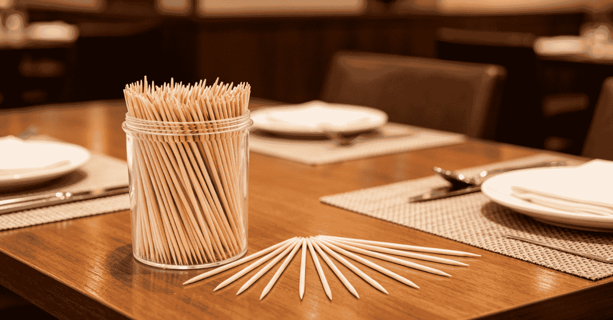 A jar of premium bamboo toothpicks on a professional restaurant dining table.