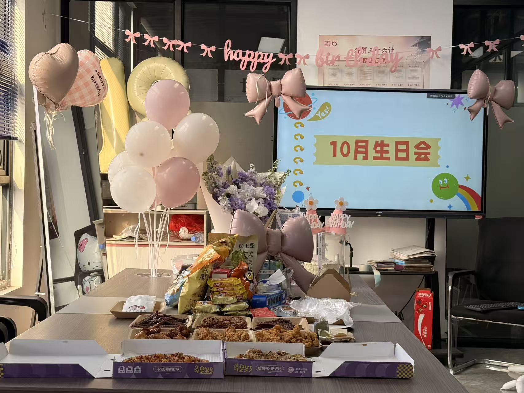 Chanjoye team birthday celebration table with balloons, flowers and snacks in front of an October birthday party screen