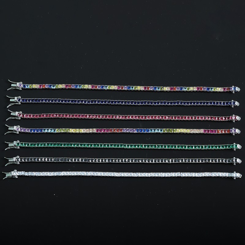 Multiple colorful square-cut tennis bracelets arranged on a dark background