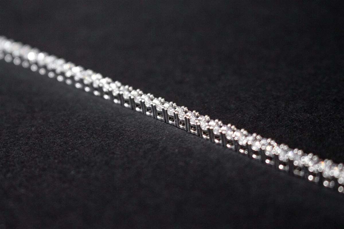 Close-up of a silver tennis bracelet on a dark background