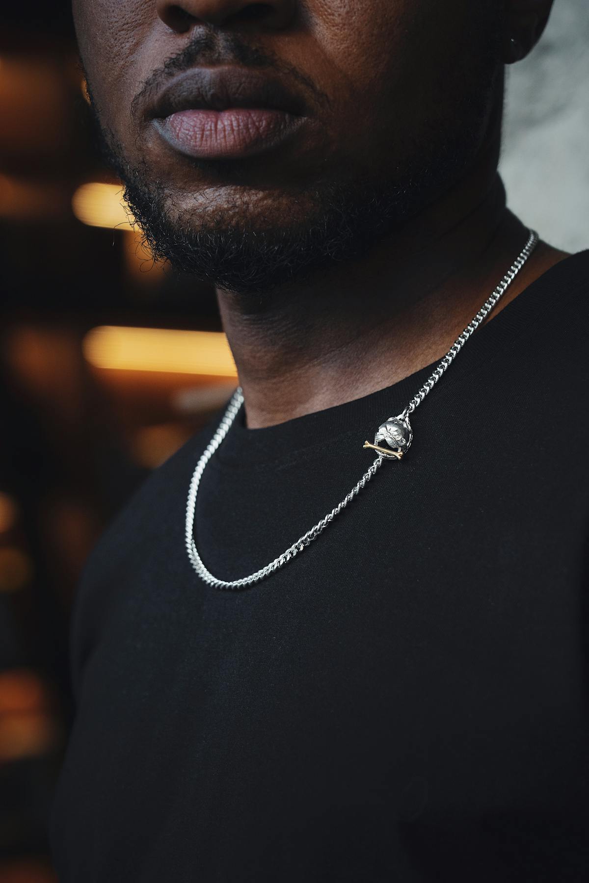 Close-up of layered silver necklaces styled on a black shirt