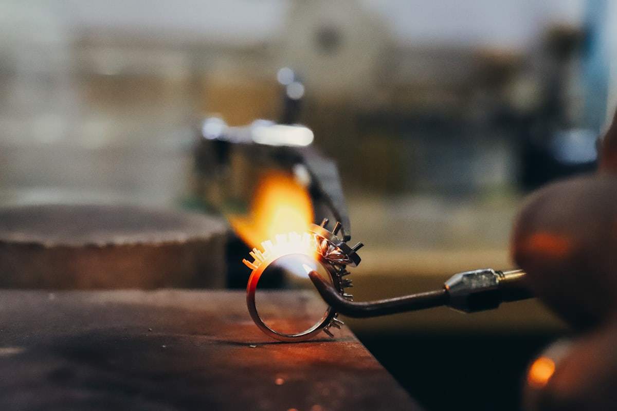 Jeweler soldering a silver jewelry ring during craftsmanship production