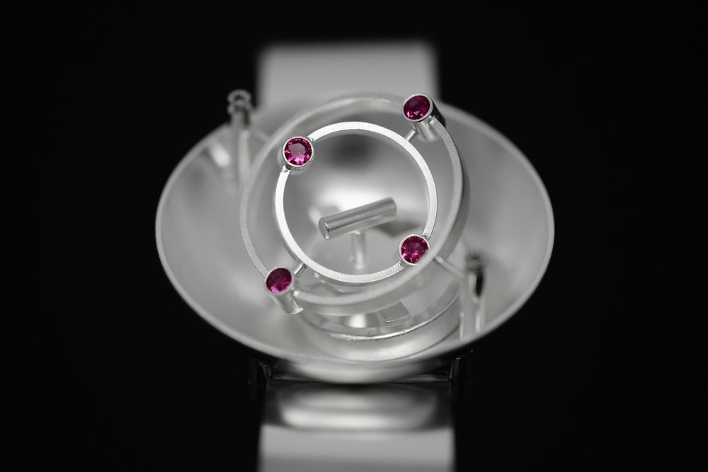 Silver ring with pink gemstones used to illustrate gemstone and setting inspection