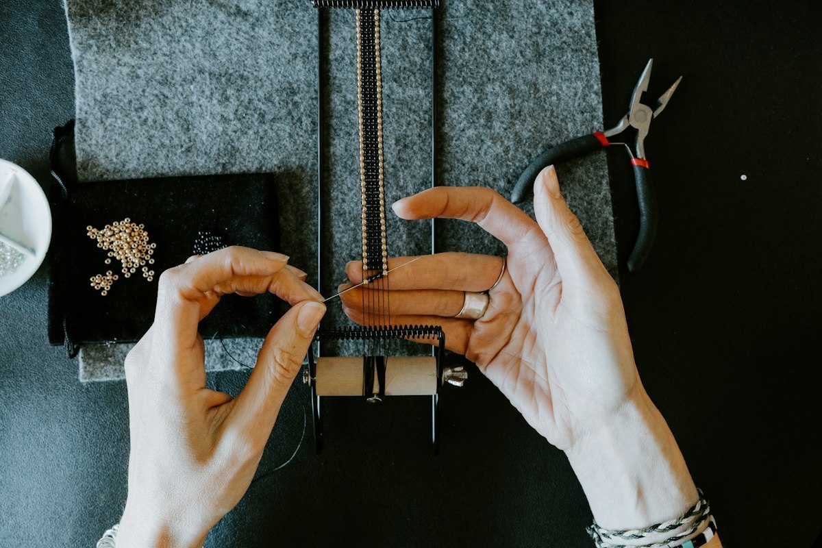 Hands assembling jewelry components at a workbench