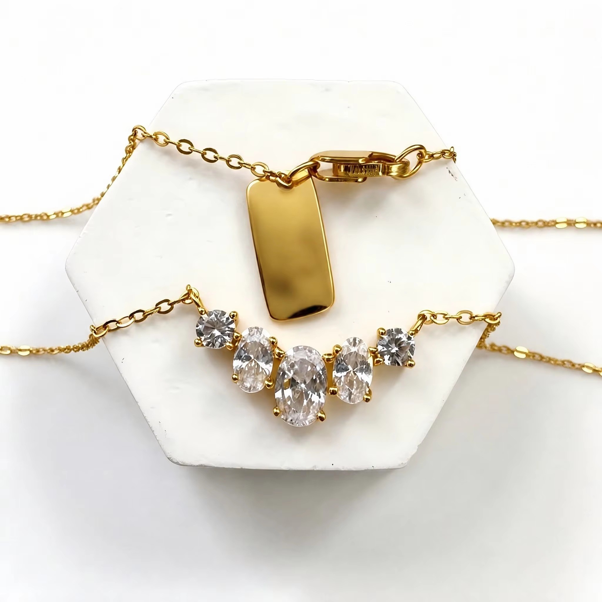 Colar dourado com etiqueta da marca e detalhe central de cristal.