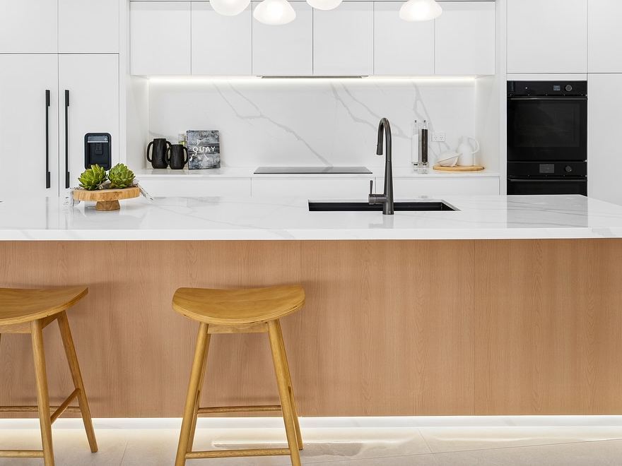 Detail of a waterfall quartz island with wood veneer base and undermount sink