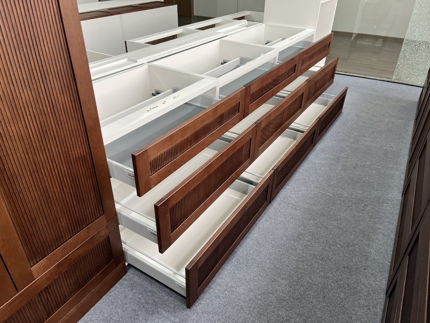 Open drawers with fluted dark wood fronts and white interiors, showing runners and internal storage configuration