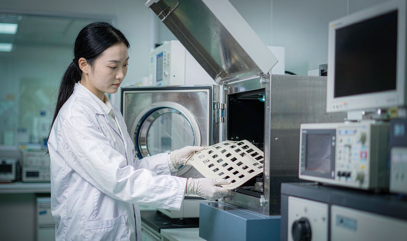 A quality engineer loading a membrane switch panel into an environmental thermal cycling test chamber in the laboratory