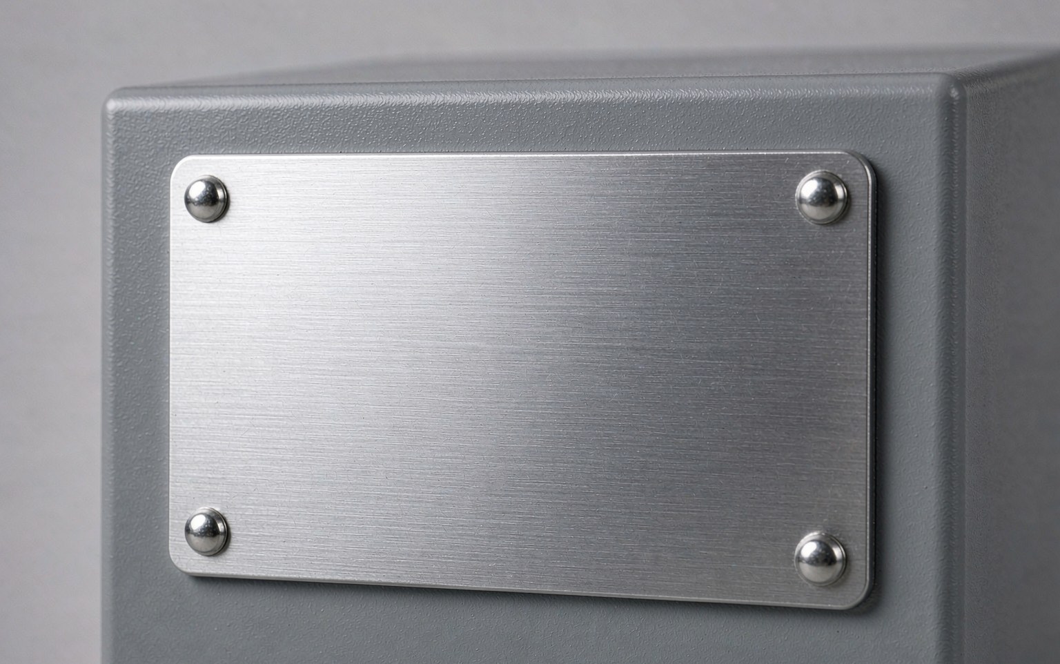 Photo of a riveted brushed metal nameplate mounted on a grey industrial machine housing