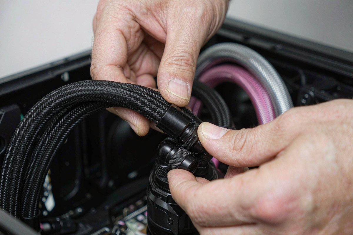 Technician routing braided tubing by hand during a PC build