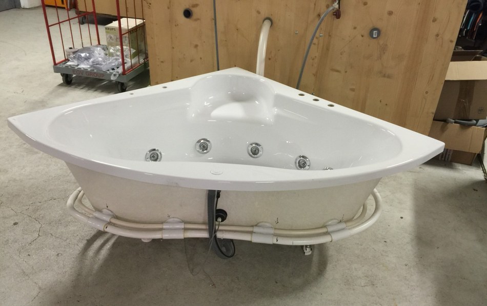 Assembled corner whirlpool bathtub at GPP Bremen with jets PVC manifold and control cable visible