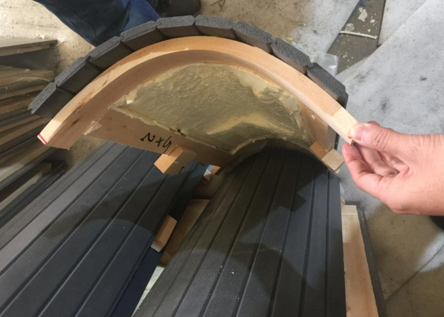 Curved SPA skirt panel with dark shingle exterior and wood frame at EEH factory