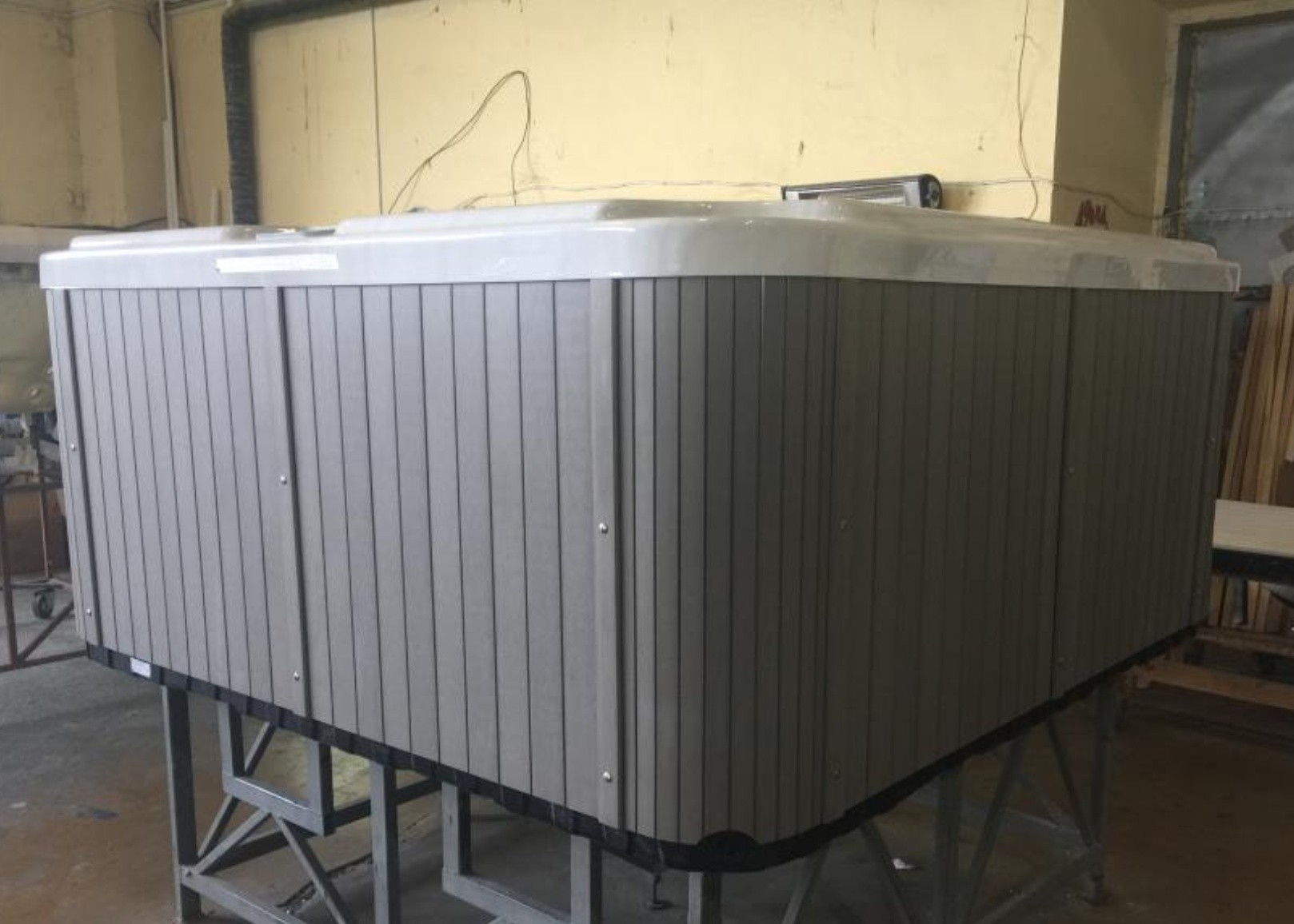 SPA with gray slatted skirt panels on metal stand at EEH factory Eastern Europe