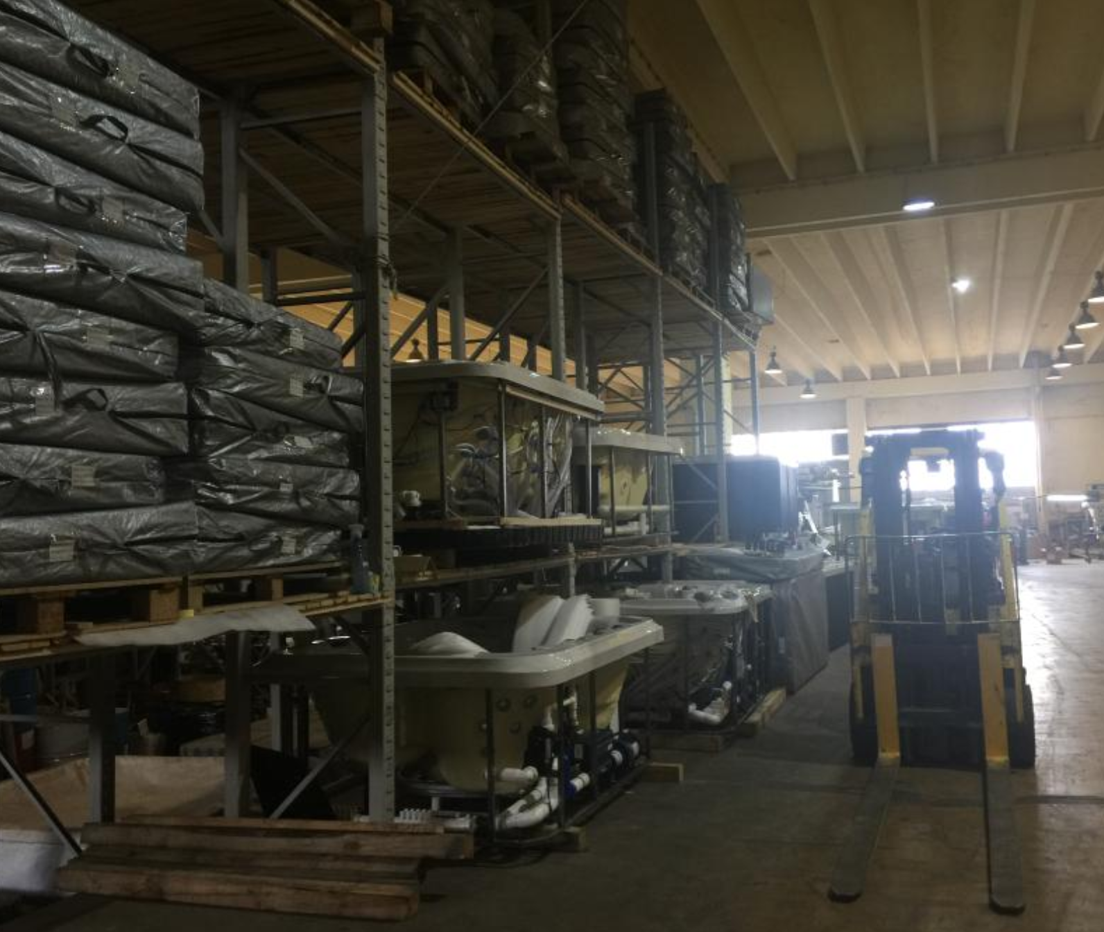 EEH warehouse with wrapped spa covers on shelving and forklift Eastern Europe