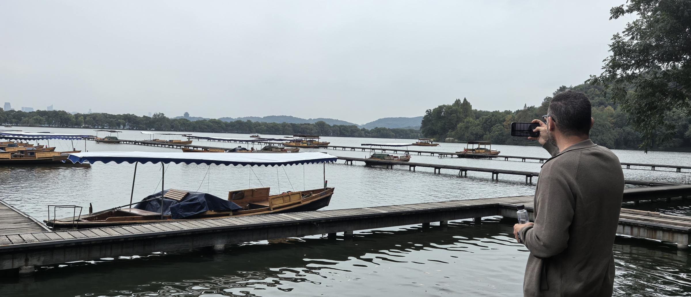 SSR customer photographing boats at a West Lake pier in Hangzhou