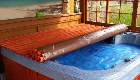 DIY wooden slat roll-up spa cover partially rolled on a hot tub