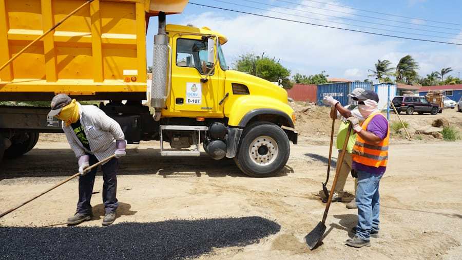 Industrial dump truck working beside road construction crews