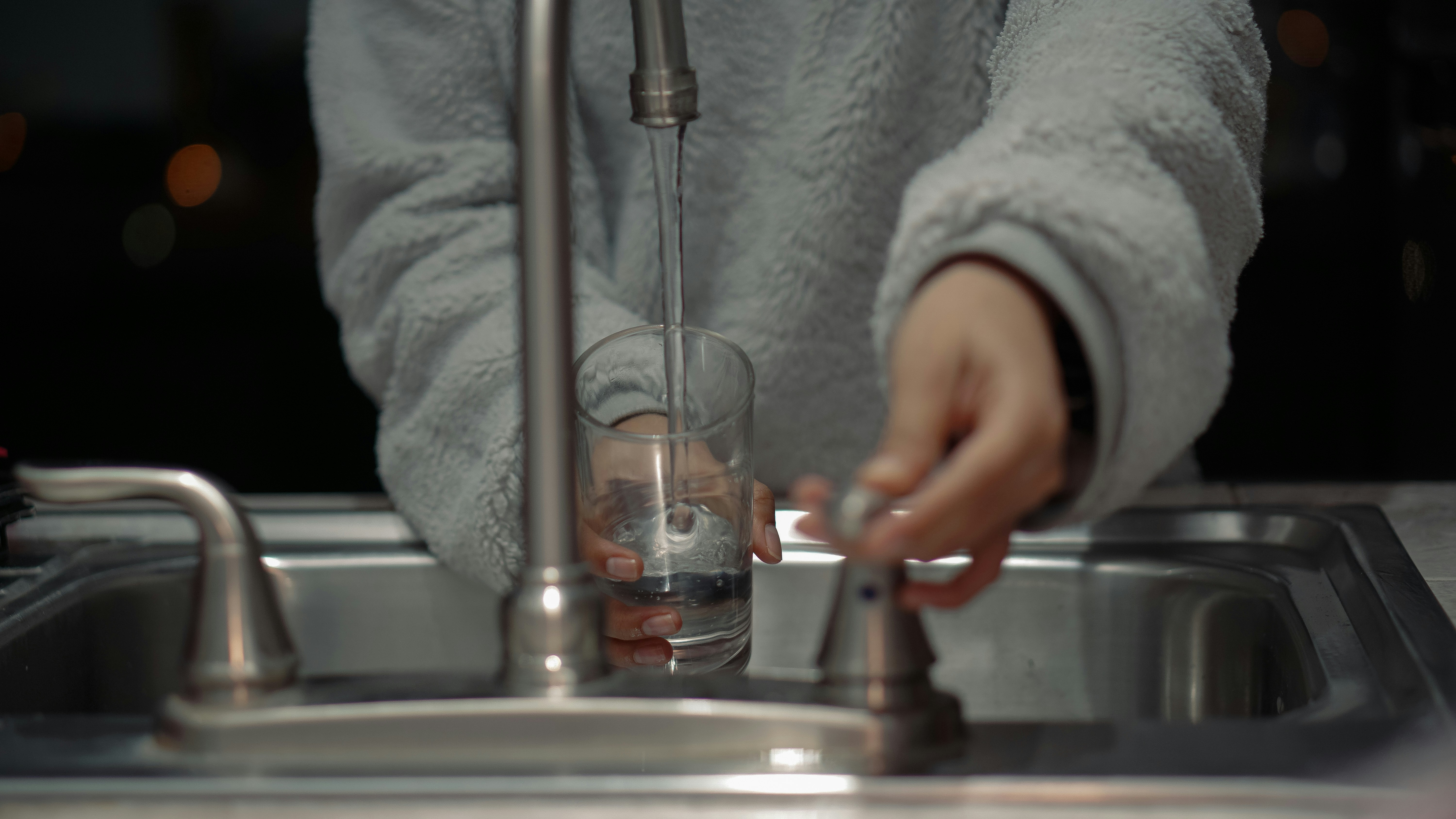 Maintenance of stainless steel sink versus concrete sink A person gently cleaning a stainless steel sink, contrasted with another person applying sealer to a concrete sink.