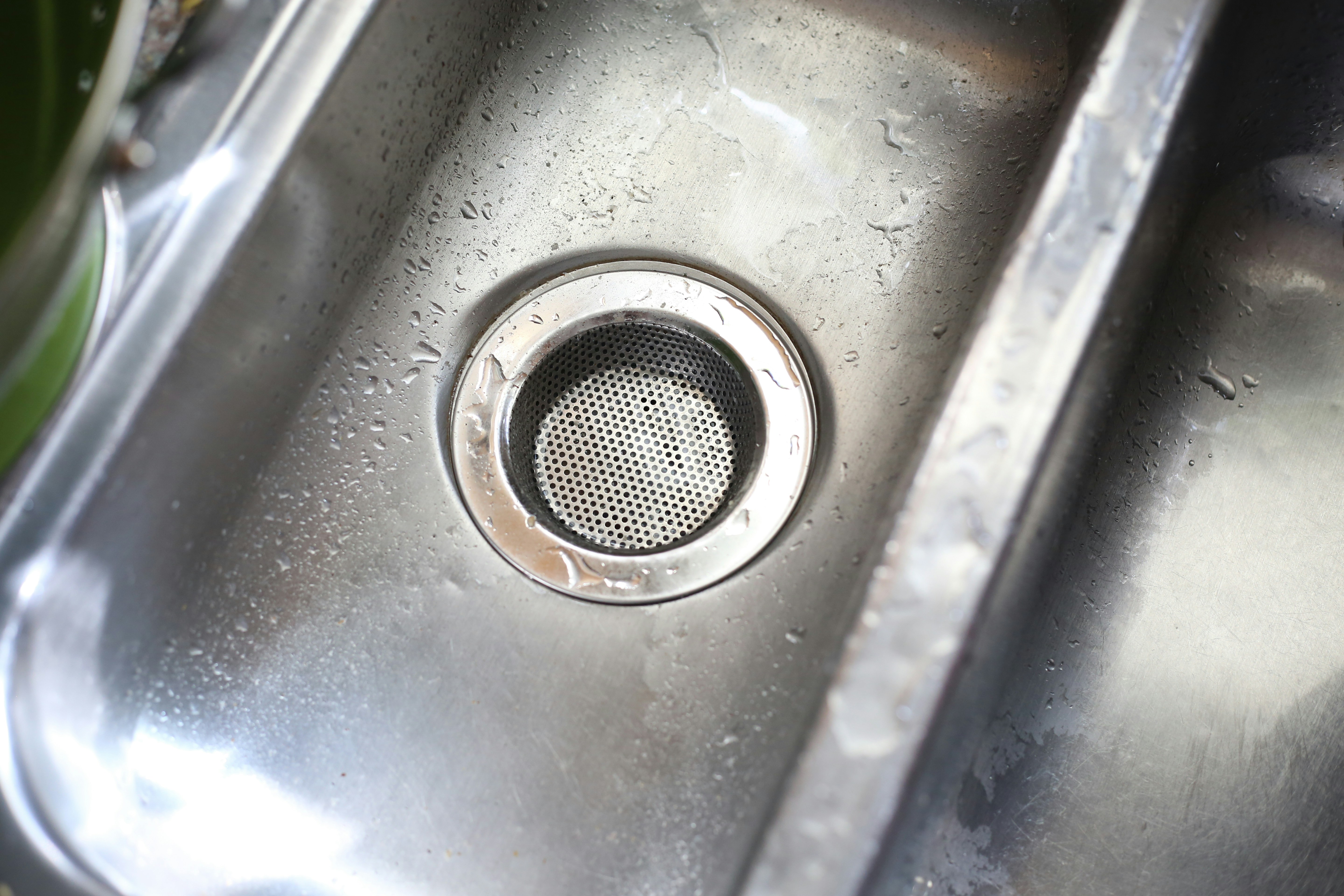 A close-up of water cascading into a clean and sanitary stainless steel sink bay.