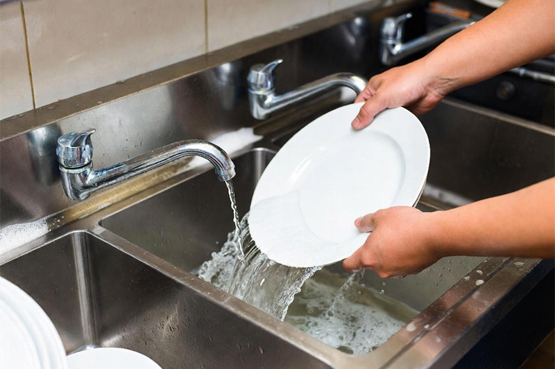Dishes and utensils air-drying on a rack in a commercial kitchen, essential for maintaining sanitation after the three-compartment process.