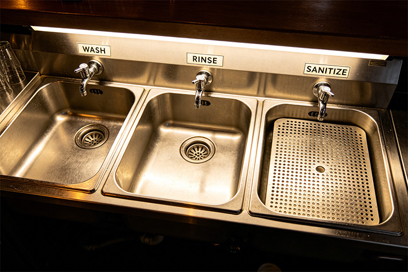 A diagram showing the five steps of the three-compartment sink method: scrape, wash, rinse, sanitize, and air dry.
