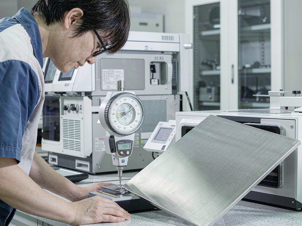 Quality engineer measuring sink steel thickness with a digital gauge