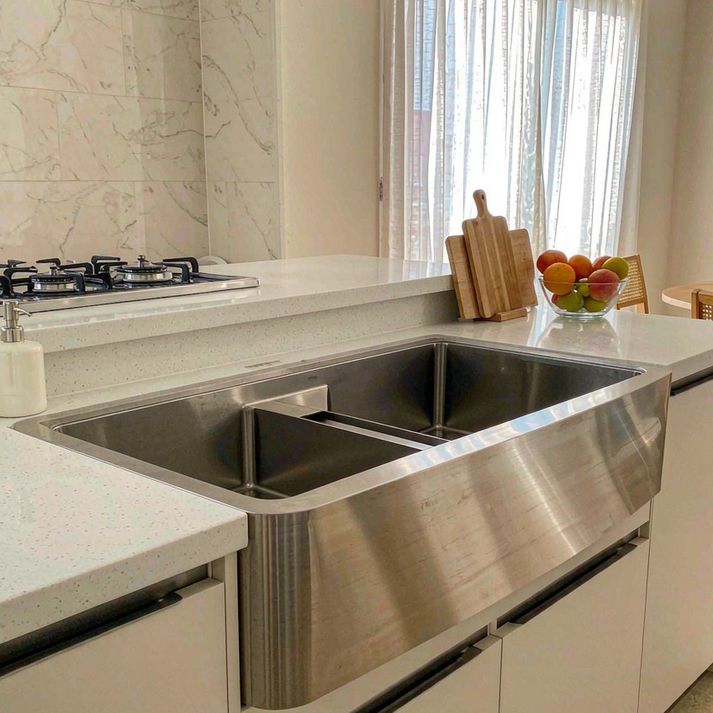 Brushed stainless steel farmhouse sink installed in a bright modern kitchen